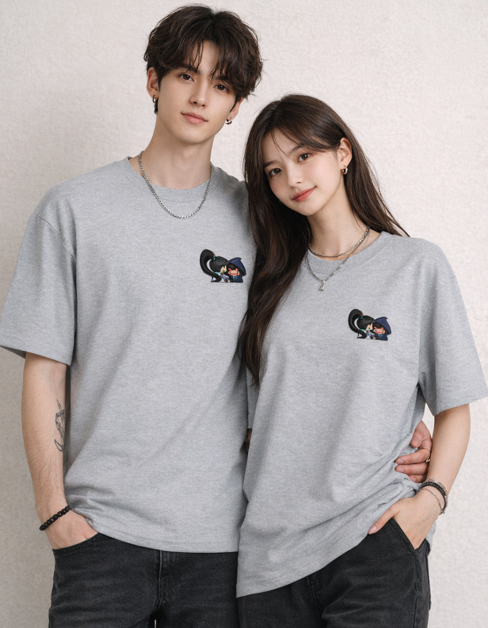 Two people wearing matching gray t-shirts with a small design on a plain background
